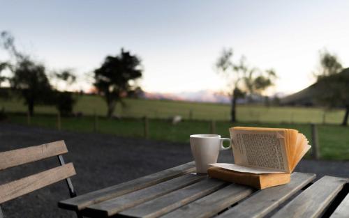 a cup of coffee and a book on a wooden table at Tussock Views by Tiny Away in Burkes Pass