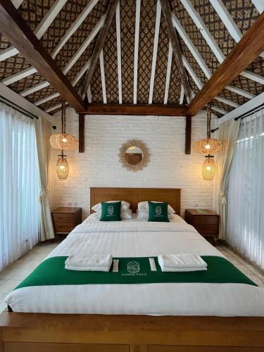 a bedroom with a large bed with two green pillows at Sampai Villa Nayan in Yogyakarta