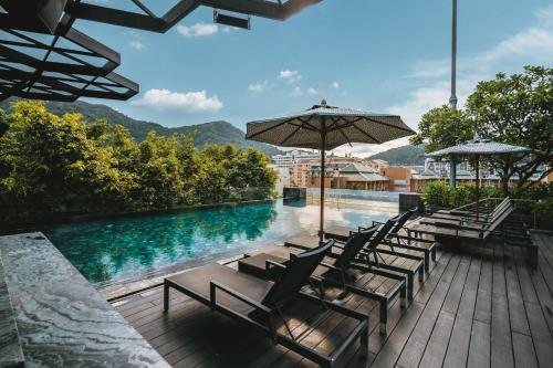 a swimming pool with chairs and umbrellas next to a pool at Hotel Indigo Phuket Patong by IHG in Patong Beach