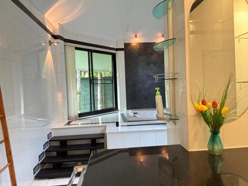 een keuken met een wastafel en een vaas met bloemen op een tafel bij Paradise House in Thai Muang