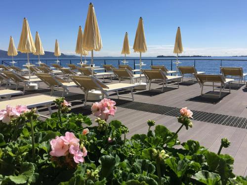 a row of chairs and tables with umbrellas and flowers at Grand Hotel Gardone in Gardone Riviera