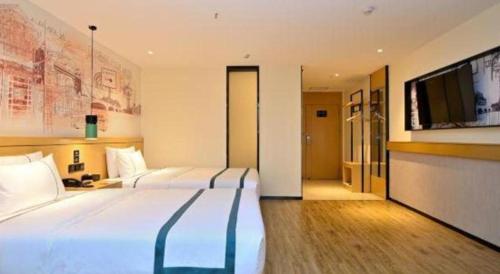 a hotel room with two beds and a flat screen tv at City Comfort Inn Kunming High Speed Railway South Station Yongxin Harvard in Kunming