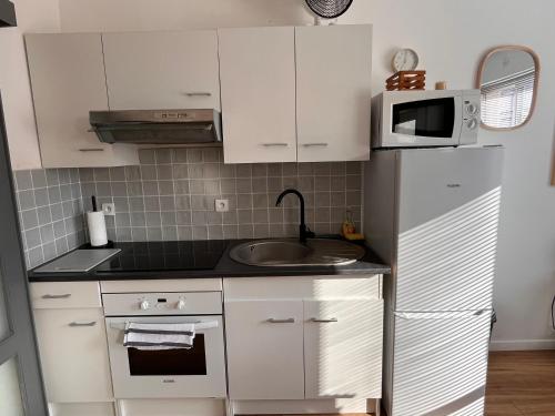 a small kitchen with white cabinets and a microwave at Hypercentre Béthune - 4 pers - Parking privé in Béthune