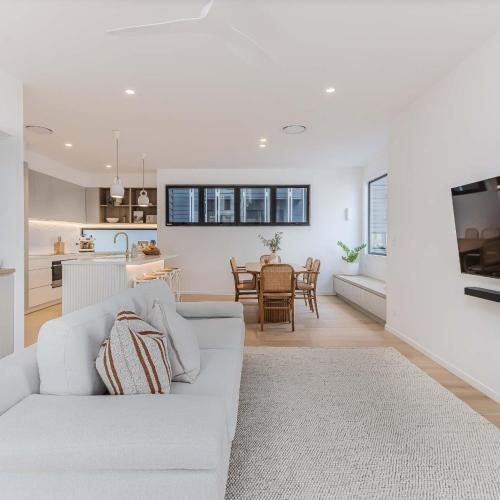 a living room with a white couch and a kitchen at Urbanstayz - Lakehouse No 2- Lakefront Luxury Escape Villa - Pet Friendly in Cabarita Beach