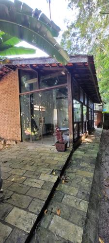 a building with glass windows and a stone patio at Pousada Shema in Itatiaia