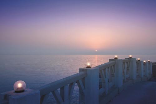 a sunset over the water with candles on a pier at Move On Beach Resort Al Khobar in Half Moon Bay
