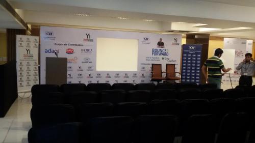 two men standing in front of a large screen at Hotel Platinum Inn in Ahmedabad