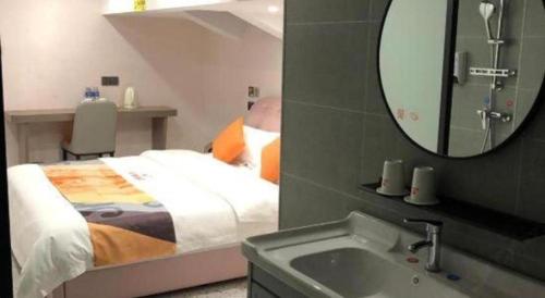 a bedroom with a bed with a mirror and a sink at Shell Hotel Shanghai Jinshan Wanda Plaza in Nanhui