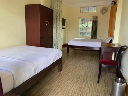 een slaapkamer met twee bedden en een stoel en een raam bij Sweet Home Guest House in Shillong