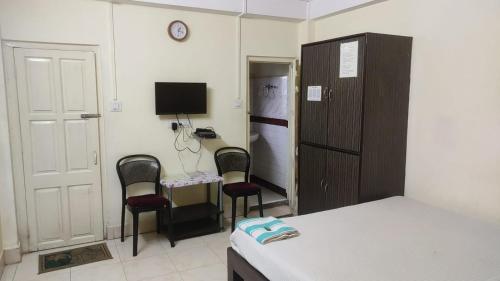 een kamer met 2 stoelen en een bureau met een televisie bij Sweet Home Guest House in Shillong
