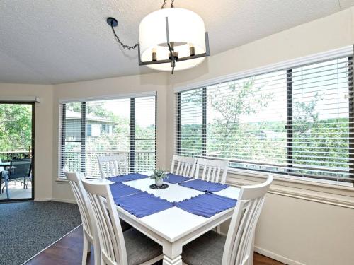a dining room with a white table and chairs and windows at Blue Agave Bungalow - Community Poolhot Tub #14 in Lakeway