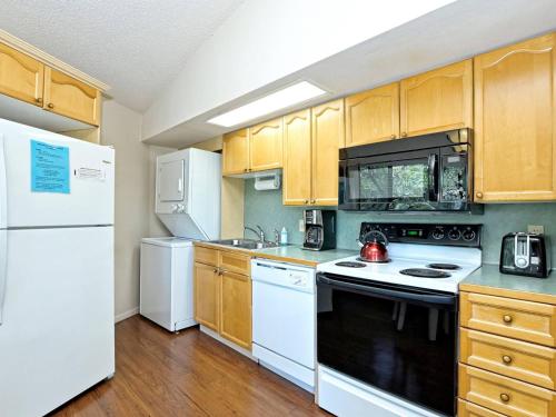 a kitchen with white appliances and wooden cabinets at Lakefront Bungalow With Community Poolhot Tub #1 in Lakeway