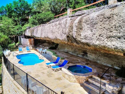 a swimming pool with lounge chairs next to a rock wall at Lakefront Bungalow With Community Poolhot Tub #1 in Lakeway