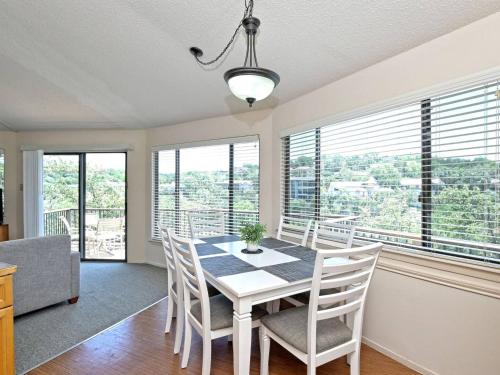 a dining room with a table and chairs and windows at Lakefront Bungalow - Community Poolhot Tub #10 in Lakeway