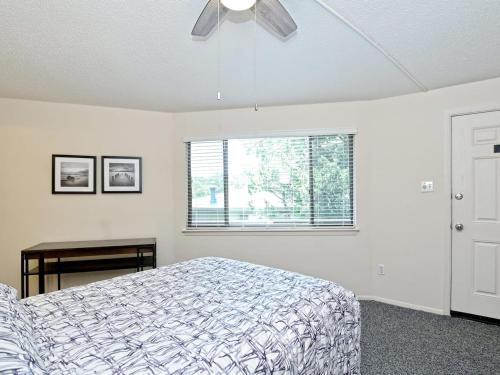 a bedroom with a bed with a ceiling fan and a window at Treehouse Bungalow - Community Poolhot Tub #17 in Lakeway