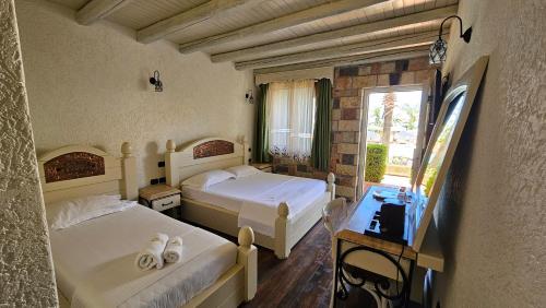 a bedroom with two beds and a desk and a window at Hotel Sarajet e Pashait 1 in Dhërmi