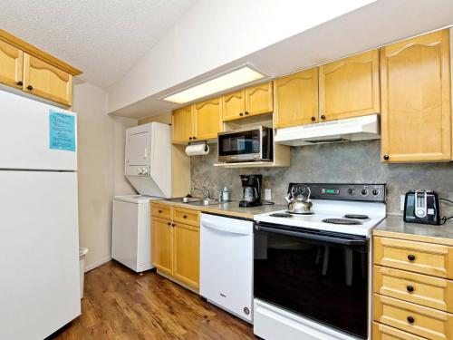 a kitchen with white appliances and wooden cabinets at Treetop Bungalow - Community Pool Hot Tub #18 in Lakeway