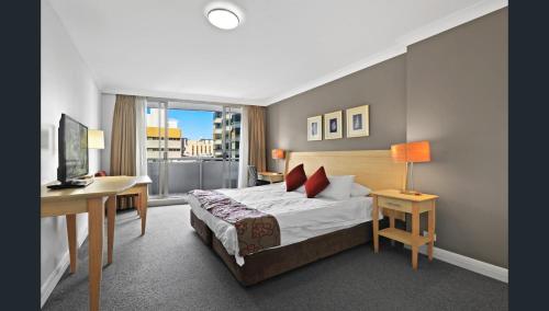 a hotel room with a bed and a desk and a computer at Spacious One-Bedroom or Studio with Balcony in Sydney