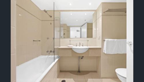a bathroom with a sink and a tub and a mirror at Spacious One-Bedroom or Studio with Balcony in Sydney
