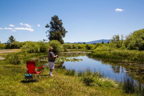 a man is standing next to a river at Bend-Sunriver Camping Resort Studio Cabin 8 in Sunriver