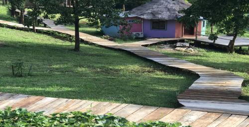 a wooden path in a garden with a house at Quiet Lodge in Krong Saen Monourom