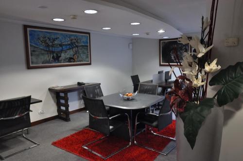 a waiting room with a table and chairs and a vase with flowers at Hotel Continental Luanda in Luanda