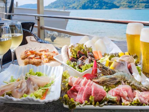 a table with three plates of food and a glass of beer at Calm Lanai Harbor in Nichinan