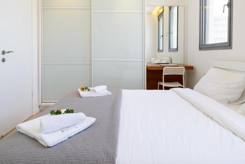1 dormitorio con 2 camas, toallas y escritorio en Comfort 3BR & Balcony in City Center by FeelHome, en Tel Aviv