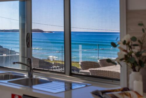 a kitchen with a view of the ocean from a window at Seabreeze on the Beach in Barrack Point