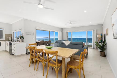 a dining room and living room with a table and chairs at Seabreeze on the Beach in Barrack Point