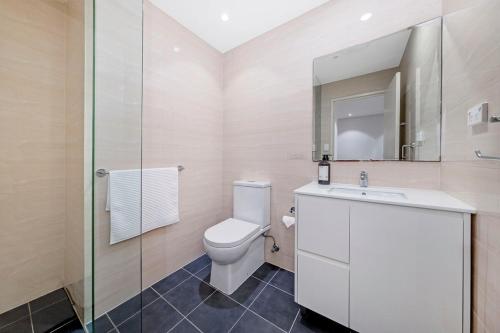 シドニーにあるStylish Homebush 1BR Plus Study with Pool Accessのトイレ、洗面台、鏡のあるバスルーム