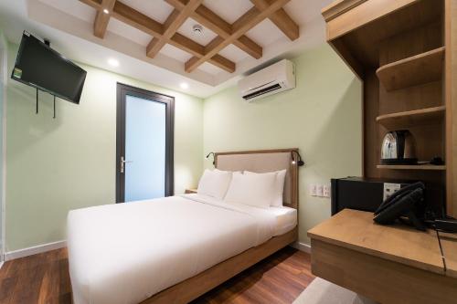 a bedroom with a white bed and a television at Nicecy Hotel - Trương Quyền in Ho Chi Minh City