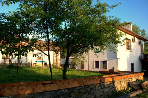 a white house with a stone wall and trees at Vedra Guest House in Ganchovets