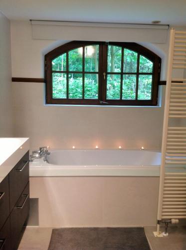 a bathroom with a bath tub and a window at Villa Sous-Bois Marie in Spa