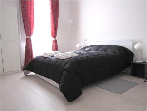 una camera da letto con un letto nero con tende rosse di Susasei a Torino