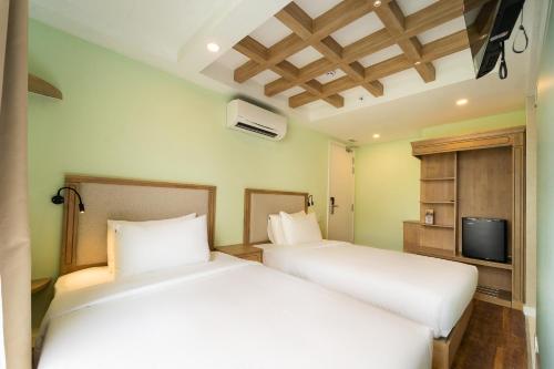 two white beds in a room with a tv at Nicecy Hotel - Trương Quyền in Ho Chi Minh City