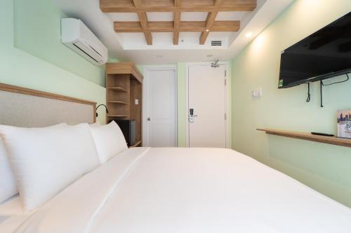 a bedroom with a white bed and a flat screen tv at Nicecy Hotel - Trương Quyền in Ho Chi Minh City