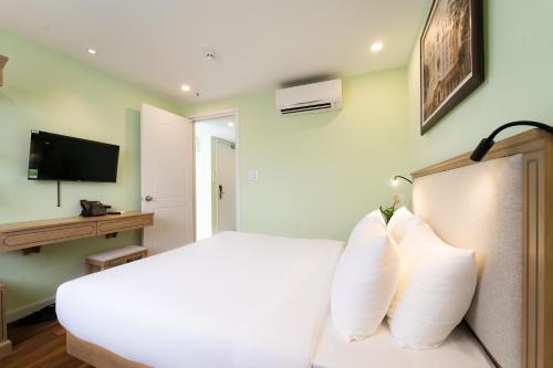 a bedroom with a white bed with white pillows at Nicecy Hotel - Trương Quyền in Ho Chi Minh City