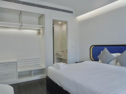 a white bedroom with a bed and a mirror at Sunset town Phú Quốc in Phu Quoc