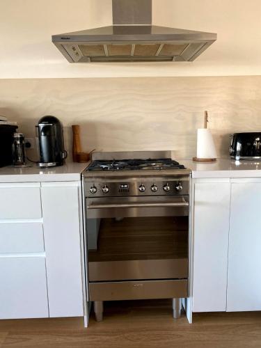 a stove in a kitchen with white cabinets at Mt Martha - Mar Vista - Panorama views with Modern coastal style in Mount Martha