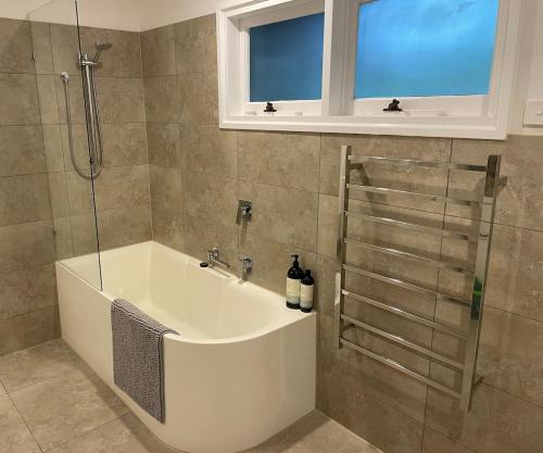 a white bath tub in a bathroom with a window at Mt Martha - Mar Vista - Panorama views with Modern coastal style in Mount Martha