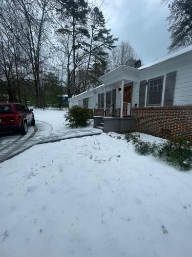 a house with snow in front of a driveway at Pine Haven Getaway -Crib, Pets Welcome, Perfect for Families & Groups in Birmingham