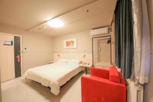 a bedroom with a bed and a red chair at Jinjiang Inn Ulanqab Jining 1st Middle School in Ulanqab