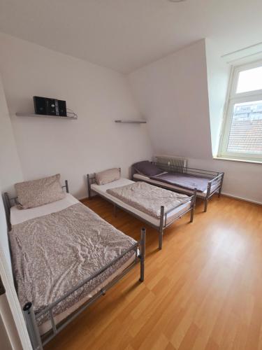 a room with three beds and a window at 2 Montage oder Ferienunterkunft in Oberhausen in Oberhausen
