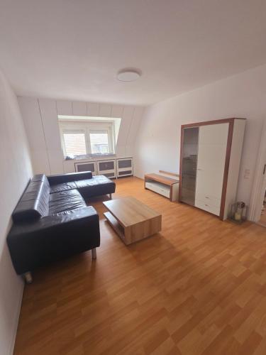 a living room with a black leather couch and a wooden floor at 2 Montage oder Ferienunterkunft in Oberhausen in Oberhausen