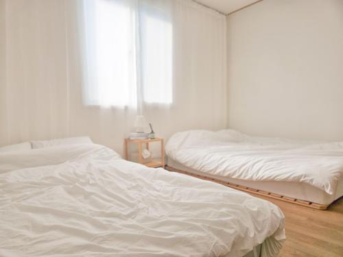 two white beds in a room with a window at Sillim Queen House in Seoul