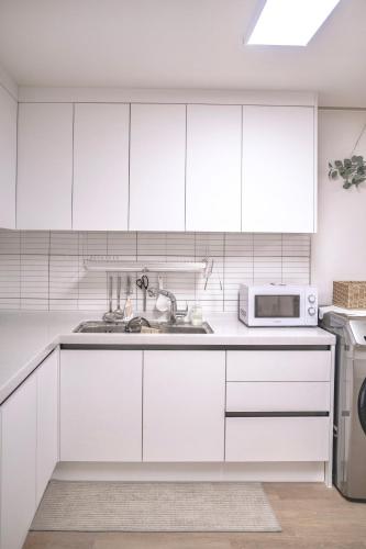 a white kitchen with a sink and a microwave at Sillim Queen House in Seoul