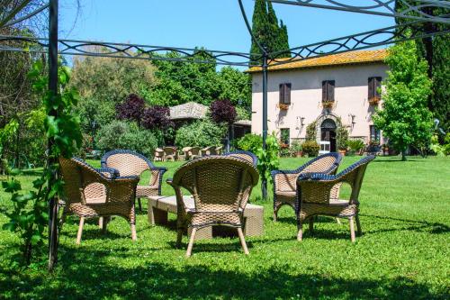 a group of chairs sitting in the grass near a building at Borgodoro - Natural Retreat in Magliano Sabina