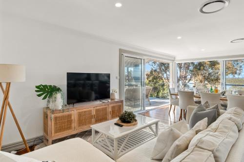 a living room with a couch and a tv at Diamond Head Manor - Pool, Water Views, Central in Budgewoi