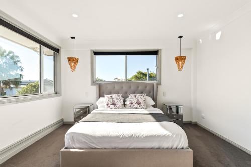 a bedroom with a large bed and two windows at Diamond Head Manor - Pool, Water Views, Central in Budgewoi
